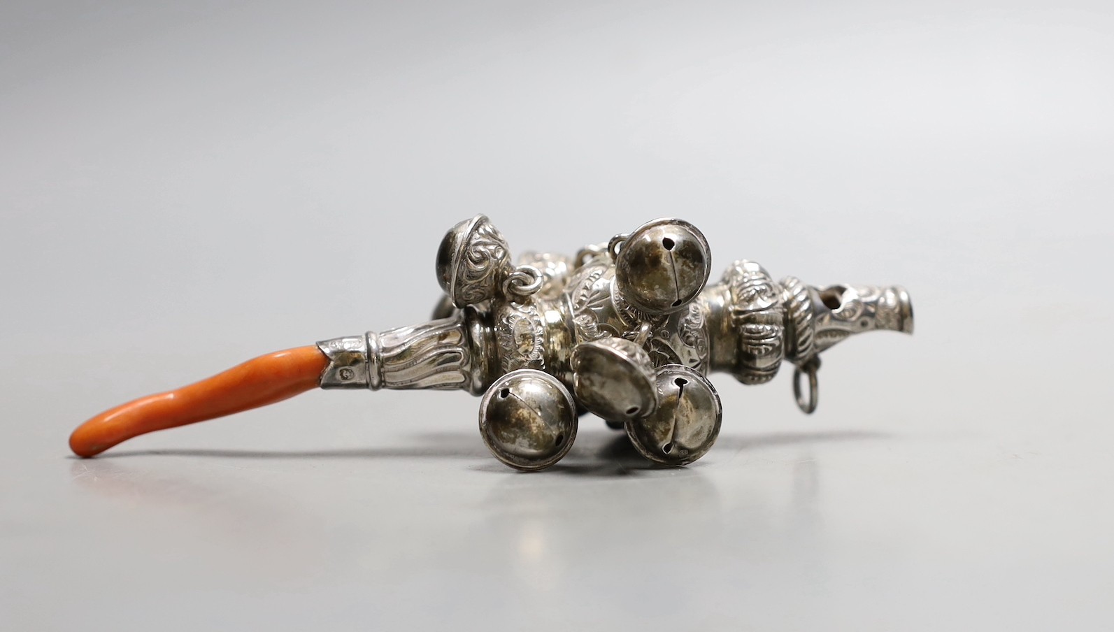 A late Victorian silver baby’s rattle, with bells, whistle and coral teether, Hilliard & Thomasson, Birmingham, 1900, 12.3cm.